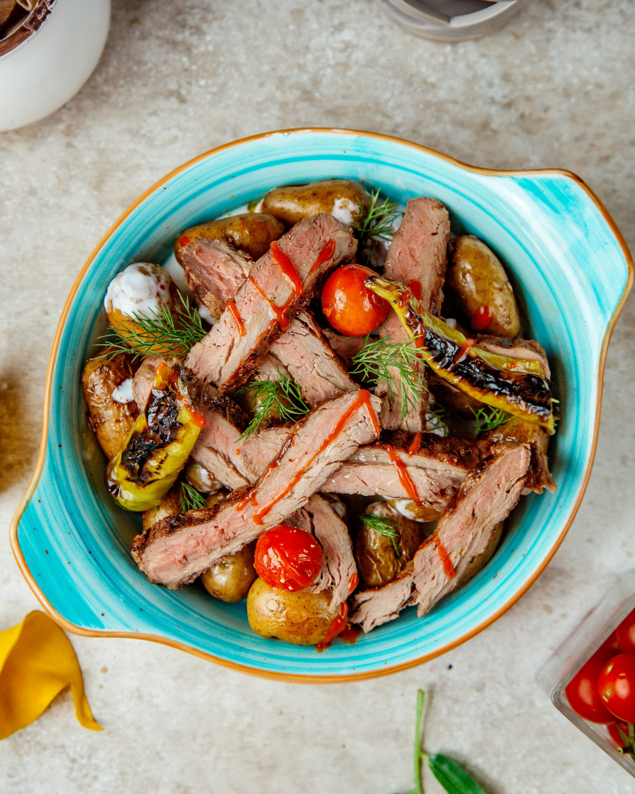 baked meat and potatoes in the oven with tomatoes and peppers top view